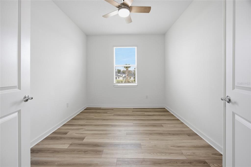 An empty room with white walls, wood-look flooring, a ceiling fan, and a single window — 4311 SW 84TH STREET, OCALA, FL