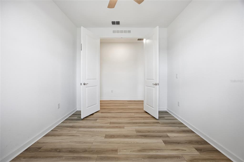 A room with white walls and wood-look flooring features double doors leading to another space — 4311 SW 84TH STREET, OCALA, FL
