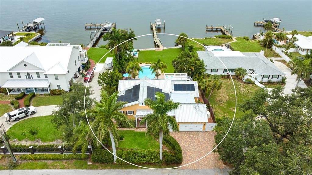 An aerial view shows a waterfront house with a pool, solar panels, and a dock — 1625 1ST AVENUE E, BRADENTON, FL