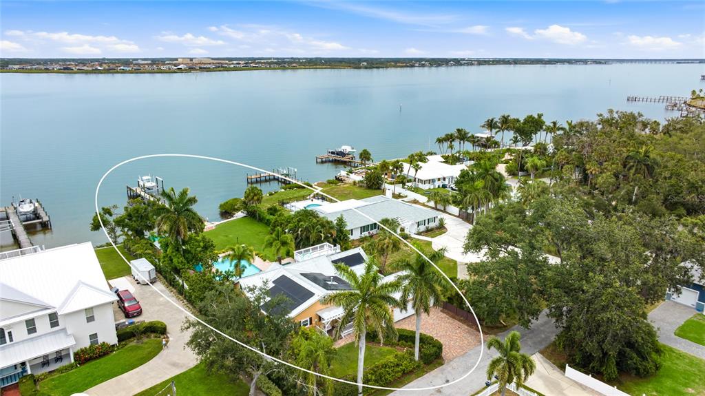 An aerial view shows a waterfront house with a pool, dock, and palm trees — 1625 1ST AVENUE E, BRADENTON, FL