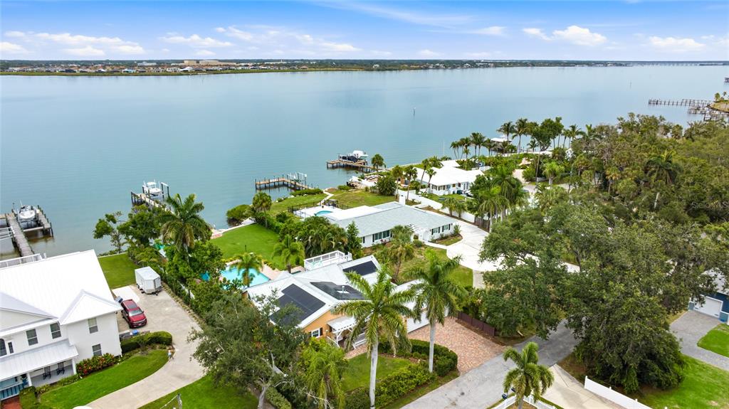An aerial view shows waterfront homes with pools, docks, and lush landscaping along a bay — 1625 1ST AVENUE E, BRADENTON, FL