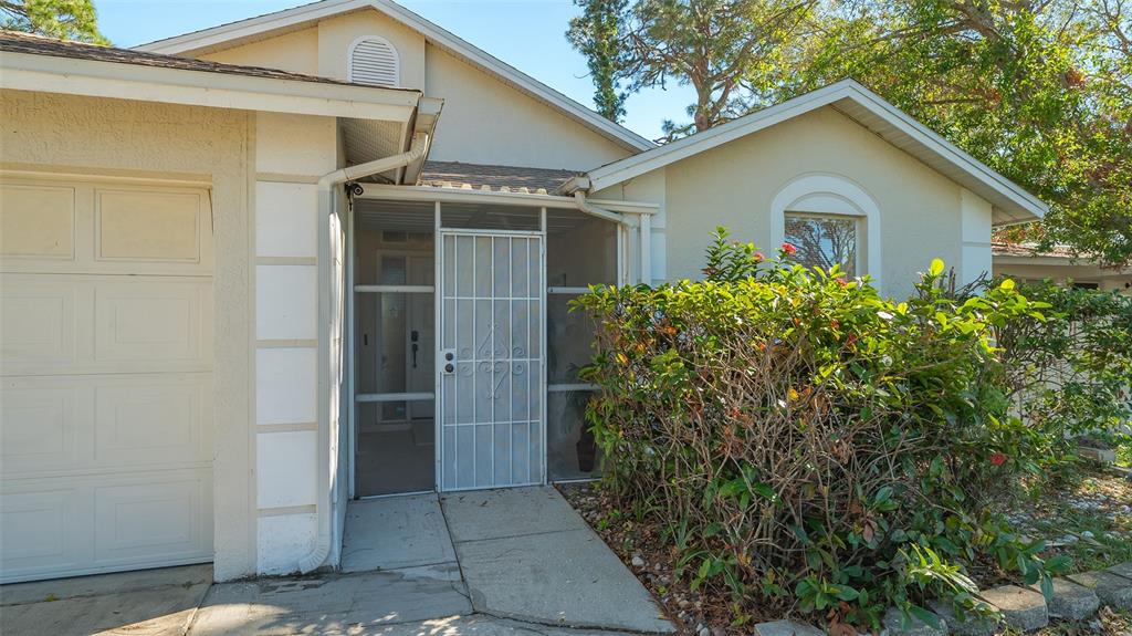 The exterior of a house features a garage, a screened entryway, and a landscaped garden — 5753 NEW YORK AVENUE, SARASOTA, FL