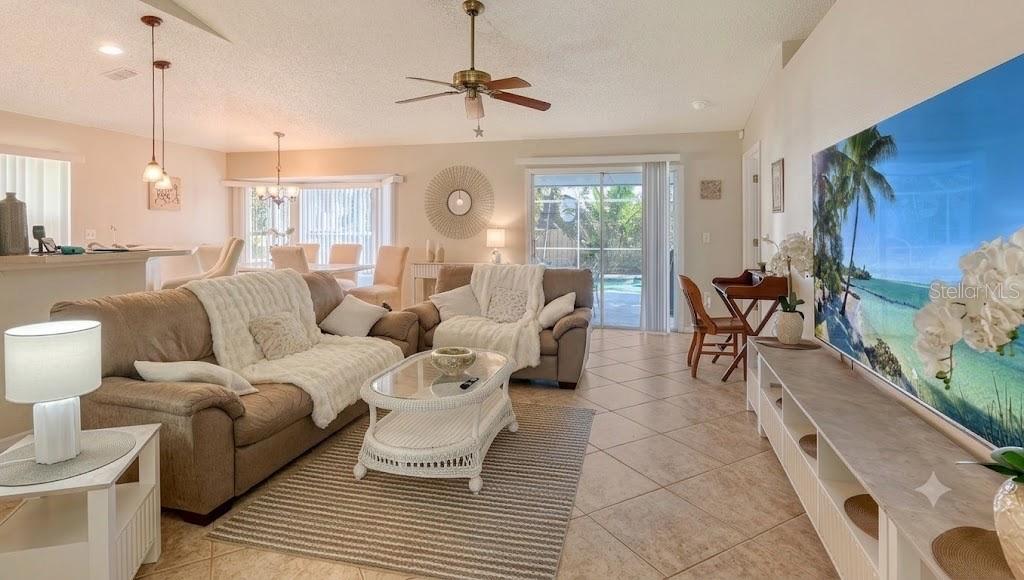 A living room features beige sofas, a white wicker coffee table, and a large wall-mounted television — 5753 NEW YORK AVENUE, SARASOTA, FL