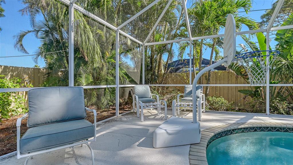 A screened-in patio features a small swimming pool, a basketball hoop, and three outdoor chairs — 5753 NEW YORK AVENUE, SARASOTA, FL