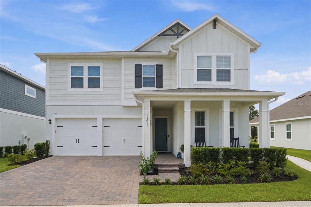 A two-story house with a white exterior, a two-car garage, and a covered front porch — 13061 SUNRISE HARVEST DRIVE, WINTER GARDEN, FL