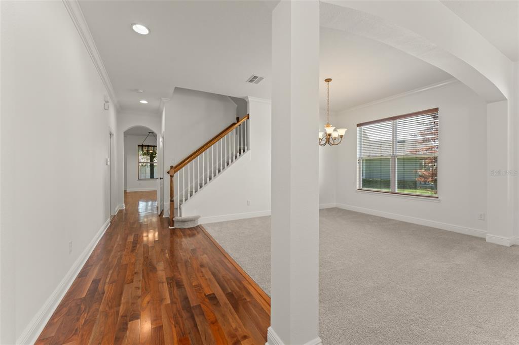 A hallway with hardwood floors leads to a carpeted dining area with an arched entryway — 13544 RIGGS WAY, WINDERMERE, FL