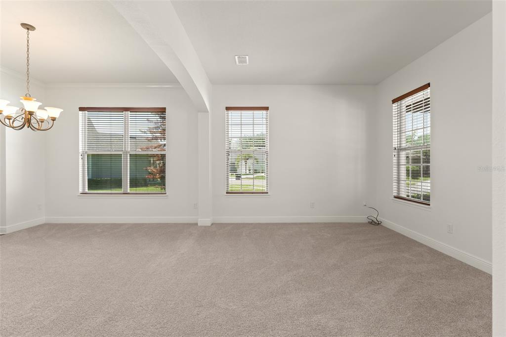 An empty room with beige carpet, white walls, and three windows with wooden blinds — 13544 RIGGS WAY, WINDERMERE, FL