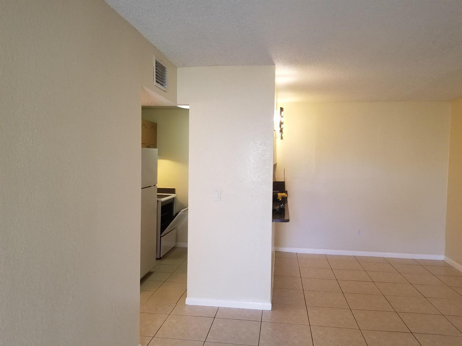A view from a tiled living area looking into a kitchen with white appliances — 6023 10th Avenue N # 114, FL 33463, FL