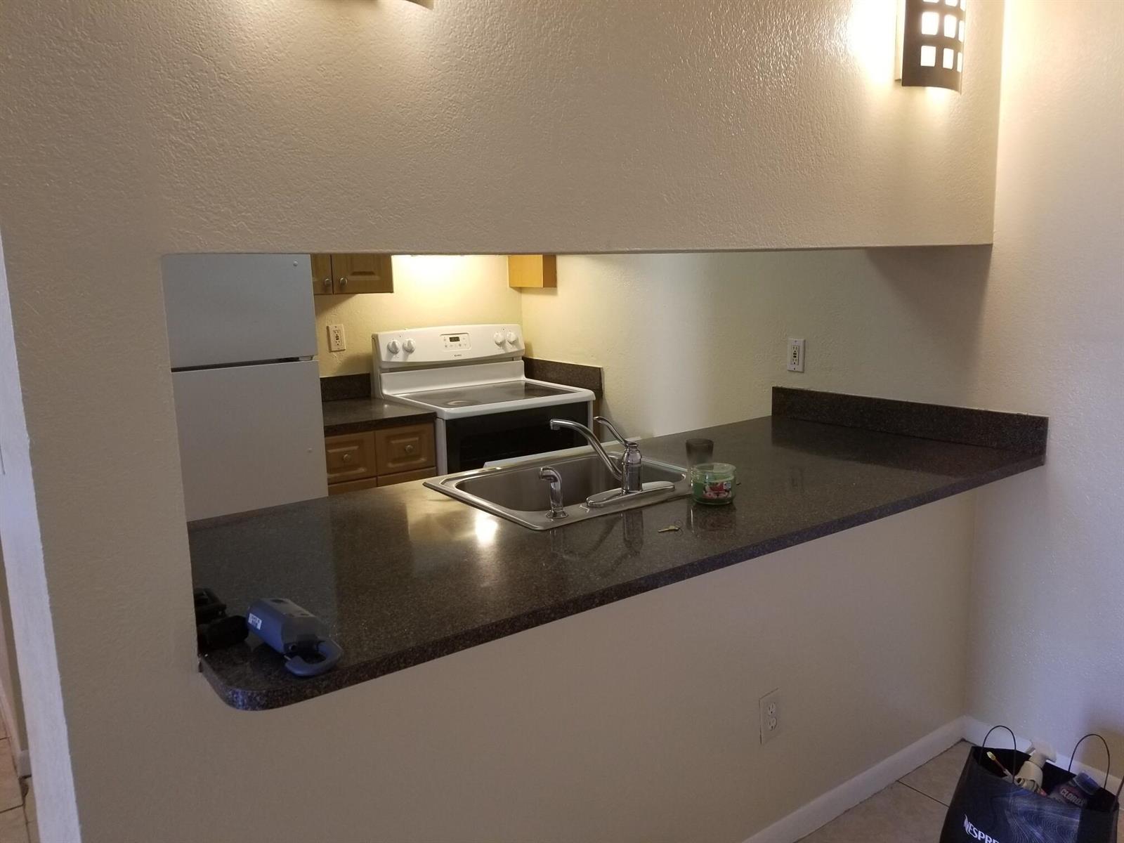 A kitchen with dark countertops, a stainless steel sink, and a white stove — 6023 10th Avenue N # 114, FL 33463, FL