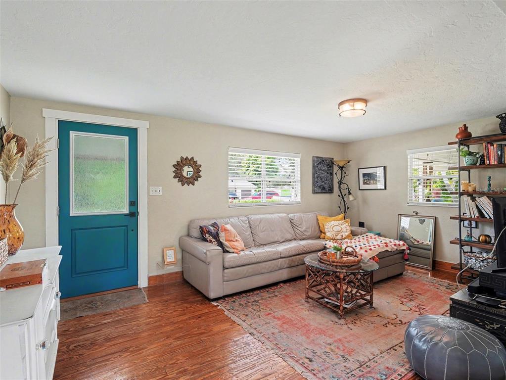 A living room features a blue front door, hardwood floors, a sectional sofa, and shelving — 3035 HILLVIEW STREET, SARASOTA, FL