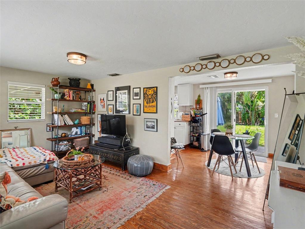 A living room with wood floors, a bookshelf, and a dining area leading to a patio — 3035 HILLVIEW STREET, SARASOTA, FL