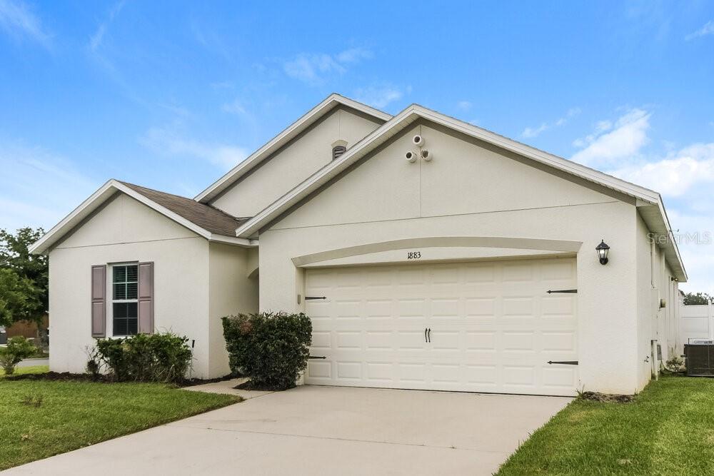 A single-story house with a white stucco exterior, a two-car garage, and a driveway — 1883 GREEN DRAGON DRIVE, ST CLOUD, FL