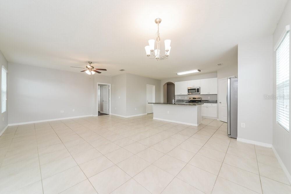 An open-concept kitchen and living area featuring light tile flooring and white cabinetry — 1883 GREEN DRAGON DRIVE, ST CLOUD, FL
