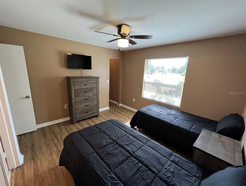 A bedroom with two beds, a dresser, a ceiling fan, and wood-look flooring — 2211 SE 3RD STREET UNIT 1, BOYNTON BEACH, FL