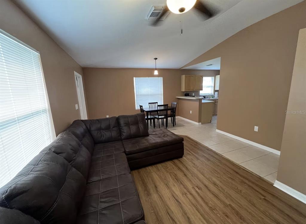 A living room with a sectional sofa, dining area, and kitchen with tile flooring — 2211 SE 3RD STREET UNIT 1, BOYNTON BEACH, FL