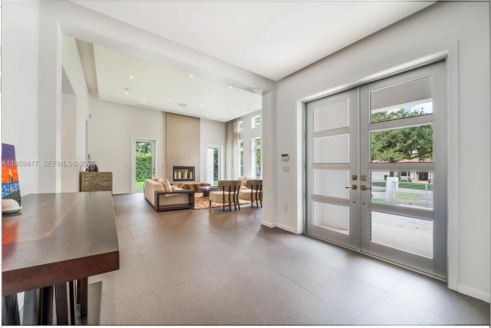 A bright, modern living room features high ceilings, large windows, and neutral-toned furniture — 6900 Barquera St, Coral Gables FL 33146, CORAL GABLES, FL