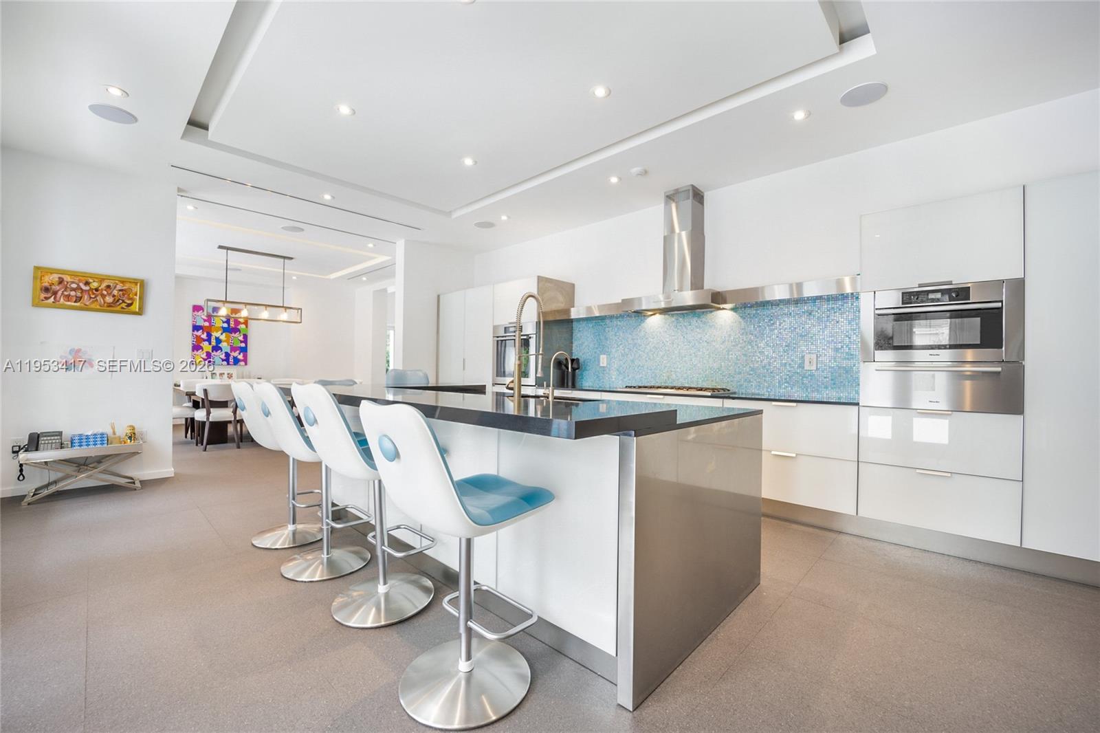 A bright living room features white furniture, a glass coffee table, and abstract wall art — 6900 Barquera St, Coral Gables FL 33146, CORAL GABLES, FL