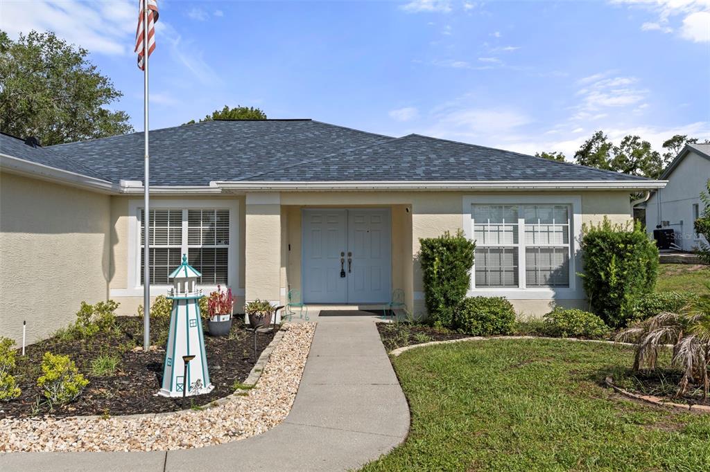A single-story house with a light-colored exterior, double front doors, and a decorative lighthouse ornament — 407 MONTPELIER COURT, SPRING HILL, FL