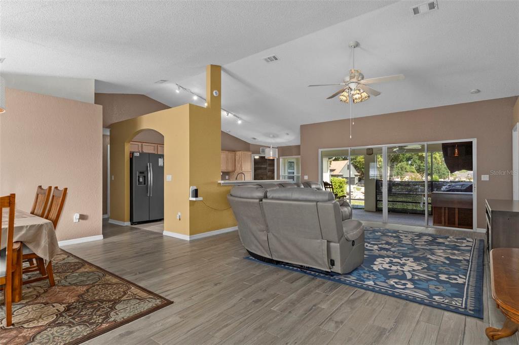 A living room with wood-look flooring, a gray sectional, and a sliding glass door — 407 MONTPELIER COURT, SPRING HILL, FL