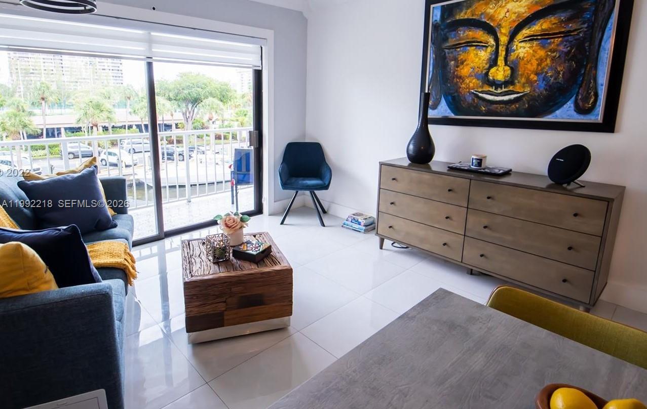 A living room features a blue sofa, a wooden coffee table, and a large Buddha painting — 1650 NE 115th St # 302, Miami FL 33181, MIAMI, FL