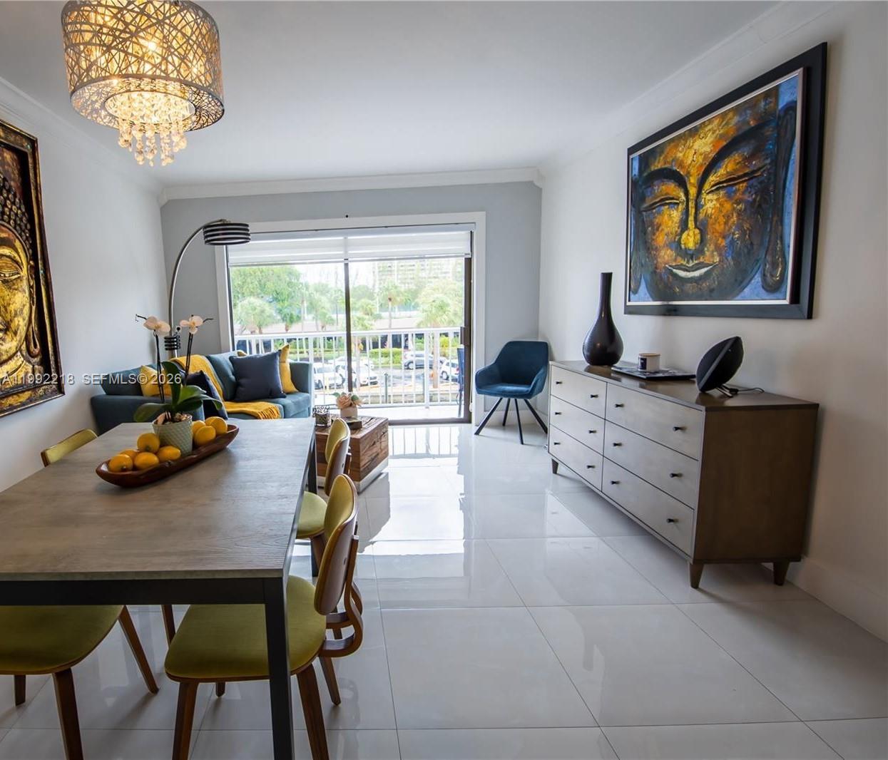 A dining and living area features a wooden table, modern chairs, and two Buddha paintings — 1650 NE 115th St # 302, Miami FL 33181, MIAMI, FL
