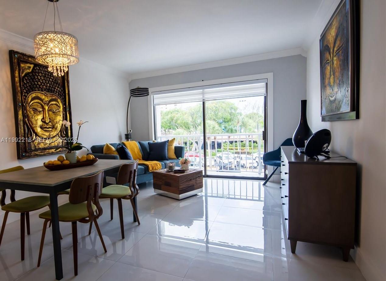 A dining and living area features tile floors, a blue sofa, and Buddha wall art — 1650 NE 115th St # 302, Miami FL 33181, MIAMI, FL