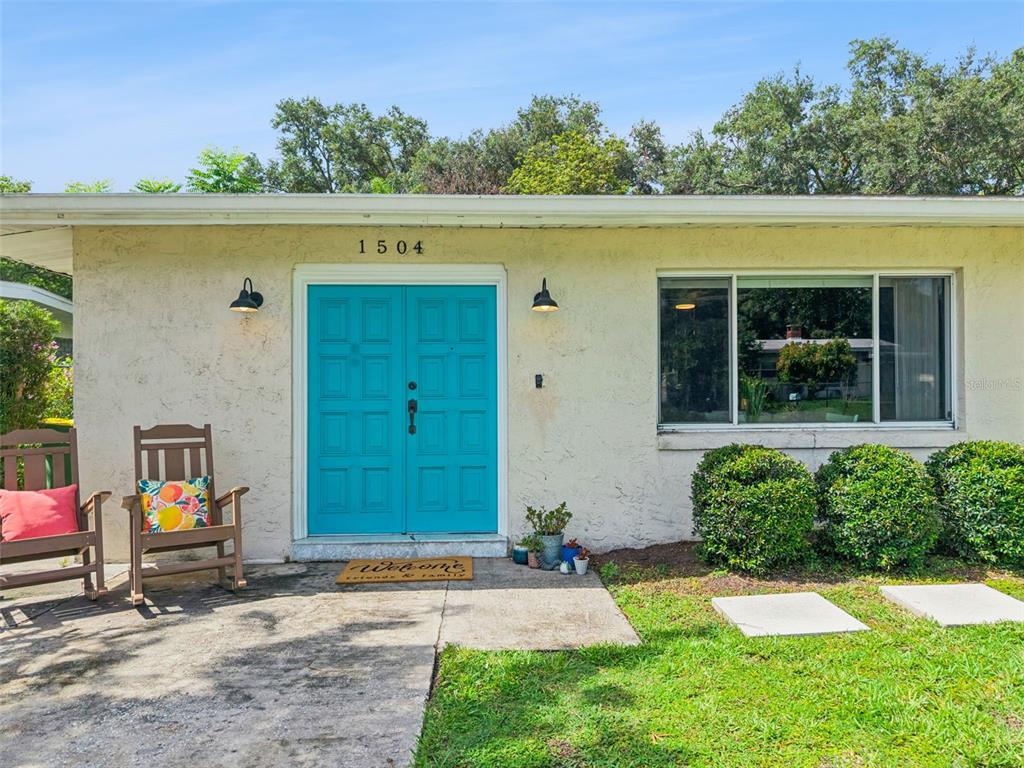 A single-story house exterior features a bright teal double front door and a large window — 1504 IDAHO AVENUE, ORLANDO, FL