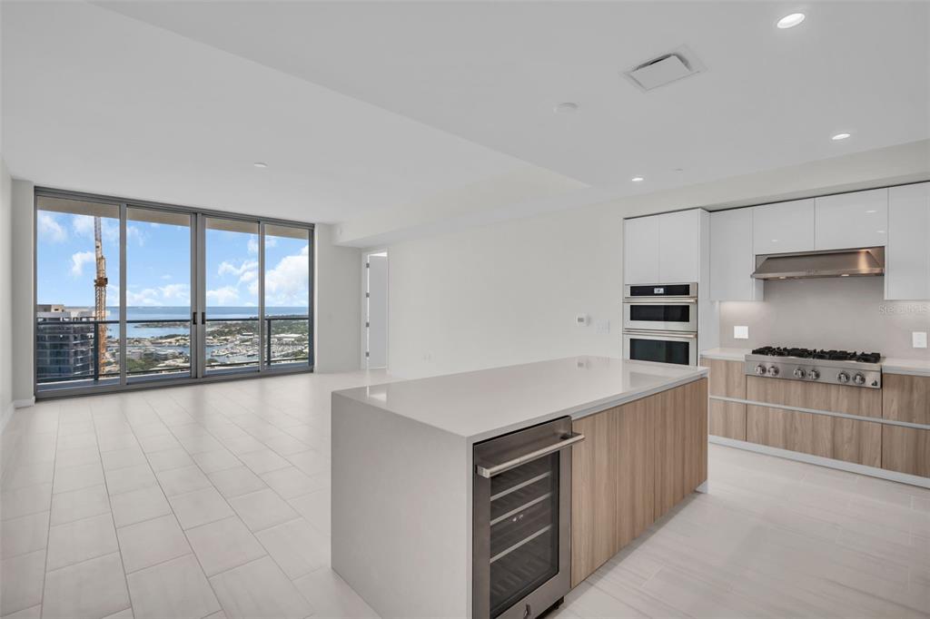 A modern kitchen with a waterfall island and stainless steel appliances overlooks a coastal view — 400 CENTRAL AVENUE UNIT 3603, ST PETERSBURG, FL