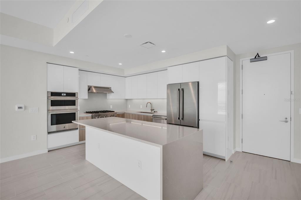 A modern kitchen features white cabinetry, stainless steel appliances, and a large quartz-topped island — 400 CENTRAL AVENUE UNIT 3603, ST PETERSBURG, FL