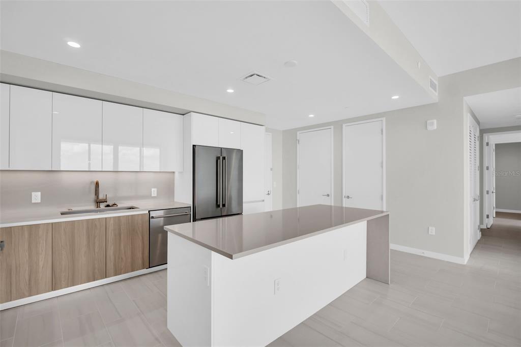 A modern kitchen features white upper cabinets, wood-tone lower cabinets, a gray island, and appliances — 400 CENTRAL AVENUE UNIT 3603, ST PETERSBURG, FL