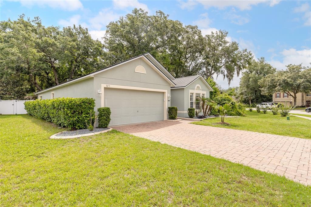 A single-story house with a light green exterior, a paved driveway, and a two-car garage — 3873 SUNSET COVE DRIVE, PORT ORANGE, FL