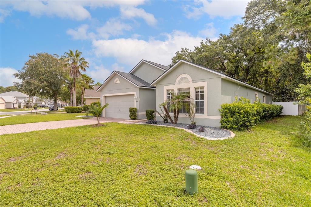 A light green single-story house with a two-car garage and a landscaped front yard — 3873 SUNSET COVE DRIVE, PORT ORANGE, FL