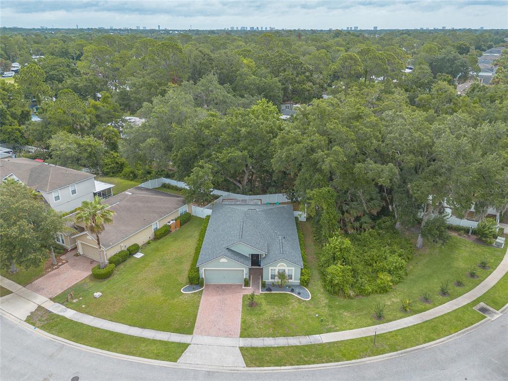 An aerial view shows a single-story house with a brick driveway and a large backyard — 3873 SUNSET COVE DRIVE, PORT ORANGE, FL
