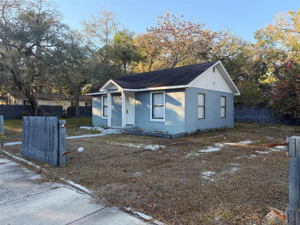 A light blue single-story house with a gabled roof sits on a dry, grassy lot — 2020 E POWHATAN AVENUE, TAMPA, FL