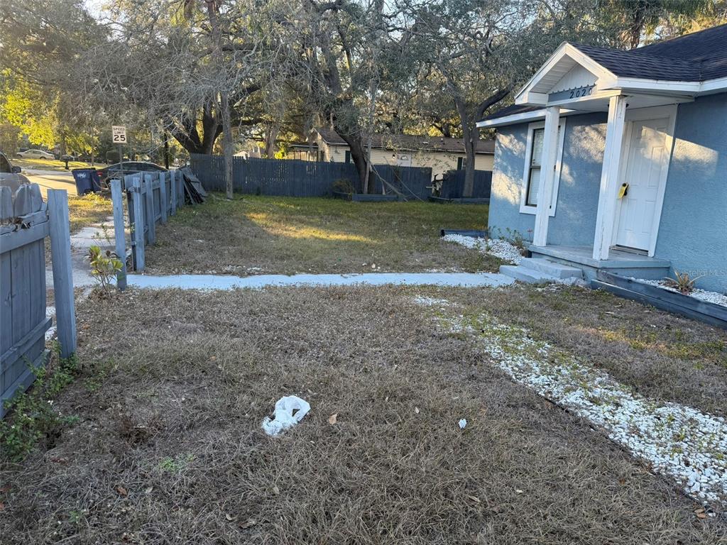 A blue house exterior features a front porch, a gravel walkway, and a wooden fence — 2020 E POWHATAN AVENUE, TAMPA, FL