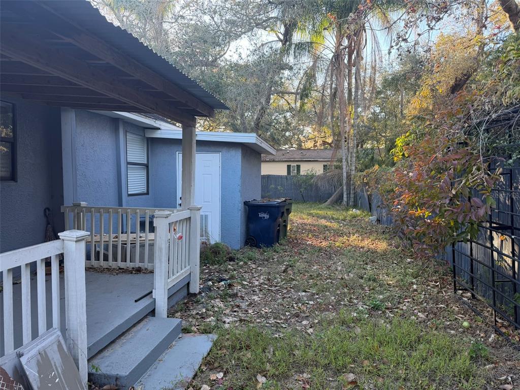 A blue house exterior features a small wooden porch, a white door, and a backyard — 2020 E POWHATAN AVENUE, TAMPA, FL