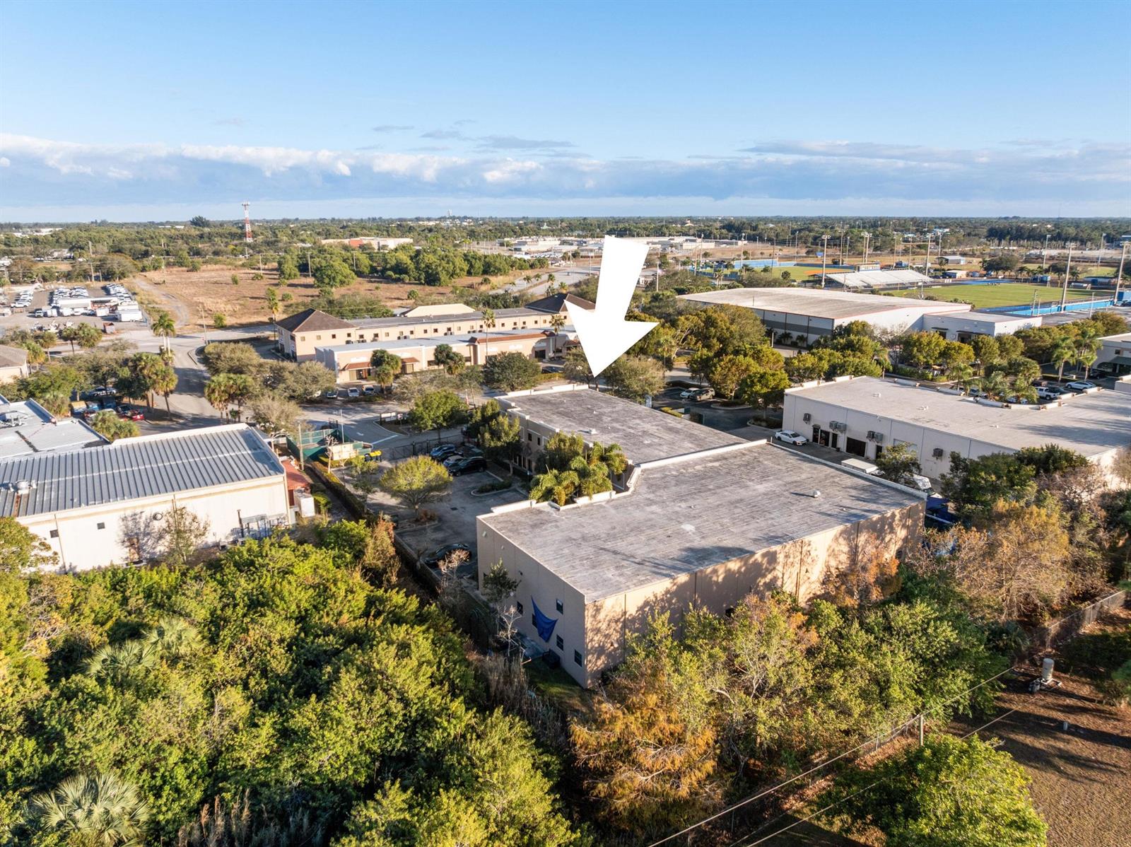 An aerial view shows a commercial building with a flat roof surrounded by trees — 2580 SE Willoughby Boulevard, Stuart FL 34994, STUART, FL
