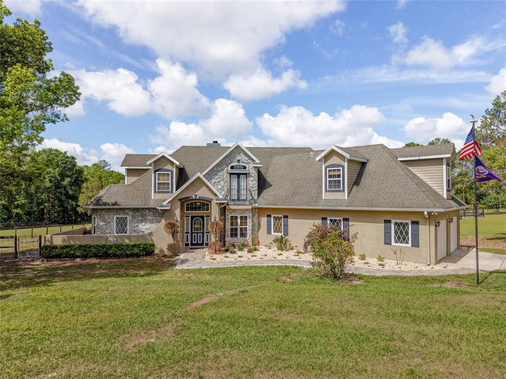 A two-story house with stone accents, a shingled roof, and a front lawn — 32640 BLUEBERRY HILL WAY, DADE CITY, FL