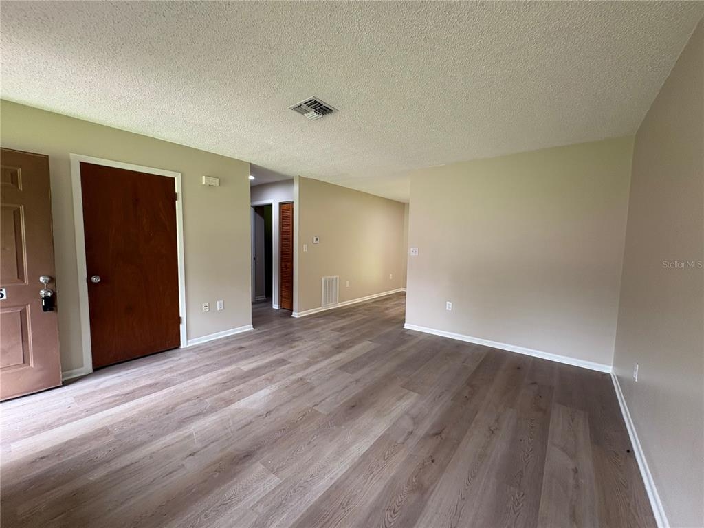 An interior view of a living area featuring light-colored wood-look flooring and beige walls — 20015 SUNCREST DRIVE, BROOKSVILLE, FL
