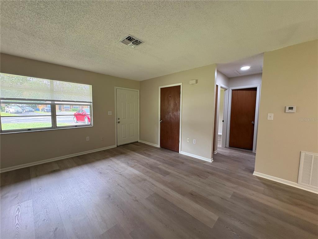 An interior view of a living room with light wood-look flooring and two wooden doors — 20015 SUNCREST DRIVE, BROOKSVILLE, FL