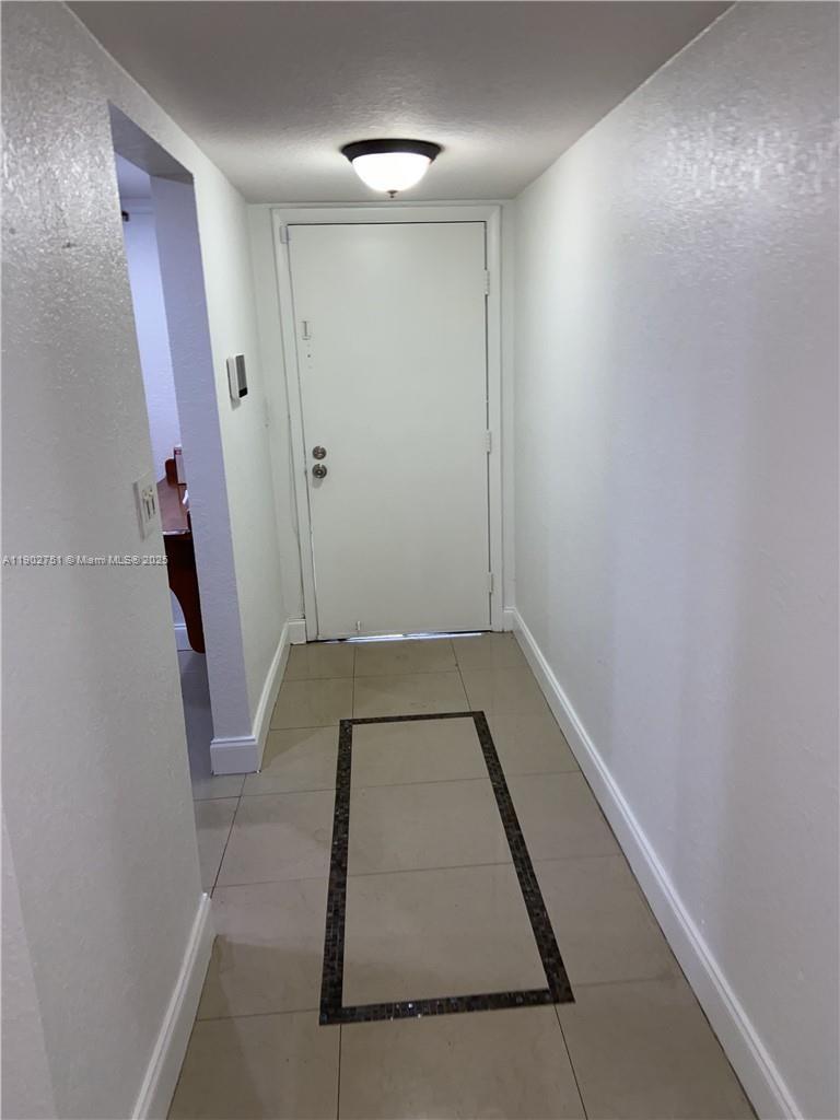 A tiled entryway features a white door, a ceiling light, and a decorative floor inlay — 3955 N Nob Hill Rd # 101, Sunrise FL 33351, SUNRISE, FL