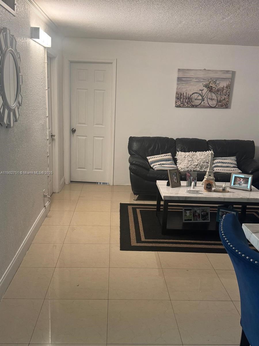 A living room features a black leather sofa, a coffee table, and tile flooring — 3955 N Nob Hill Rd # 101, Sunrise FL 33351, SUNRISE, FL