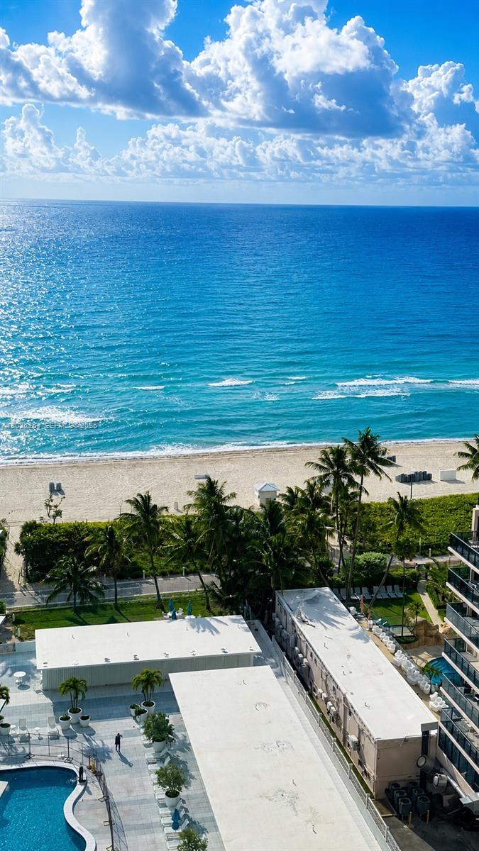 An aerial view shows a beach, ocean, palm trees, and a swimming pool area — MIAMI BEACH, FL