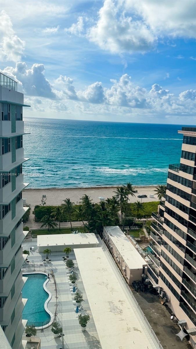 An elevated view shows a swimming pool, beach, and ocean between two high-rise buildings — MIAMI BEACH, FL