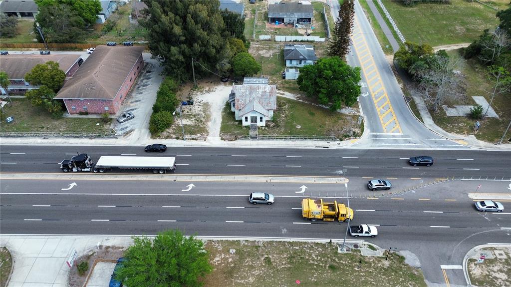 An aerial view shows a multi-lane road with vehicles passing by several buildings and trees — 980 S LAKE SHORE WAY, LAKE ALFRED, FL
