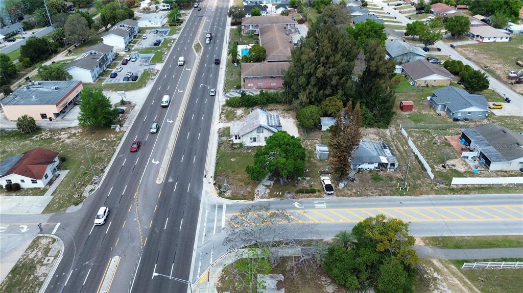 An aerial view shows a multi-lane road intersection next to several houses and commercial buildings — 980 S LAKE SHORE WAY, LAKE ALFRED, FL