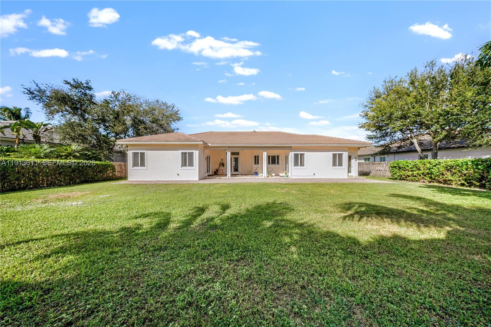The rear exterior of a single-story house features a covered patio and a large lawn — 9424 SW 123rd Ter, Miami FL 33176, MIAMI, FL