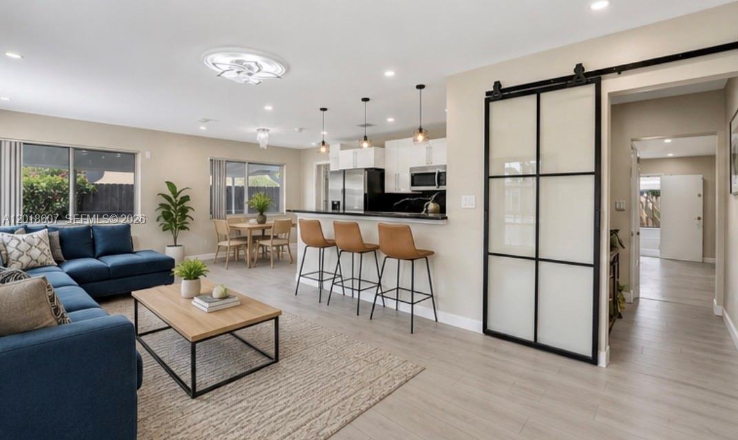 An open-concept living and dining area features a blue sectional, kitchen island, and sliding door — 3401 NW 7th St, Lauderhill FL 33311, LAUDERHILL, FL