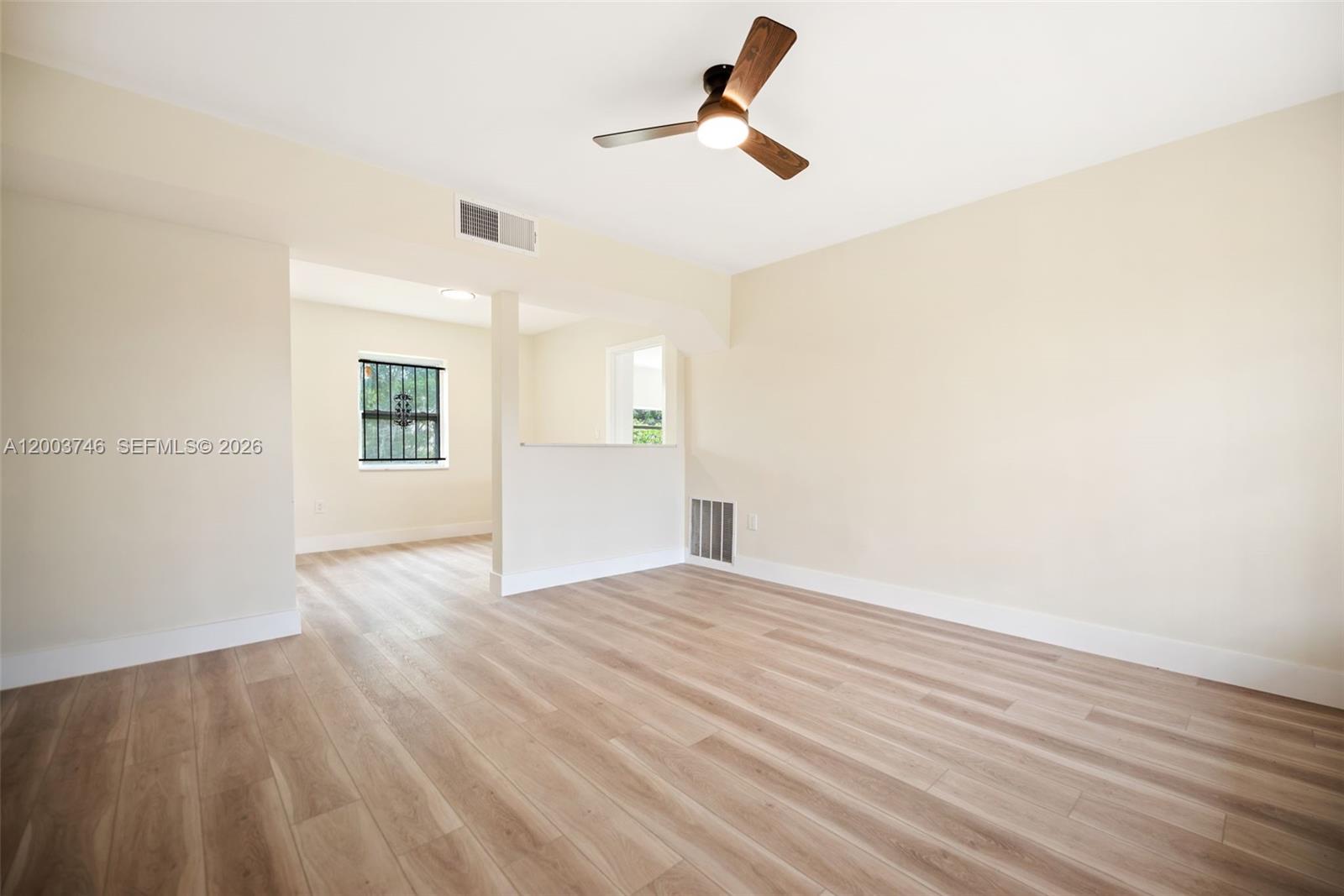 An empty room features light wood-look flooring, a ceiling fan, and a partial wall divider — 1130 NW 129th St, North Miami FL 33168, NORTH MIAMI, FL