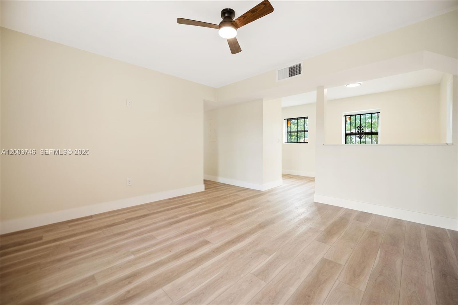 An empty room features light wood-look flooring, a ceiling fan, and an open wall cutout — 1130 NW 129th St, North Miami FL 33168, NORTH MIAMI, FL
